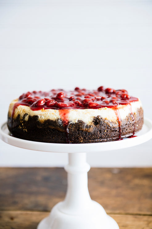 Load image into Gallery viewer, A homemade cheesecake on a cake stand topped with sour cherries