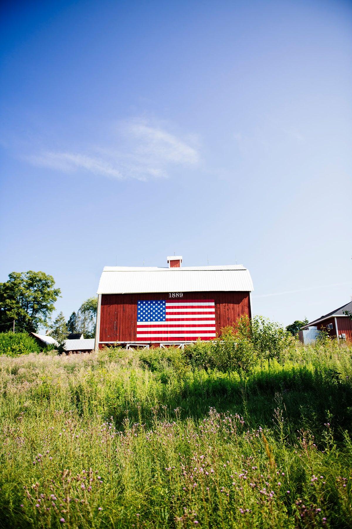 A red barn with a painted American Flag in the summer