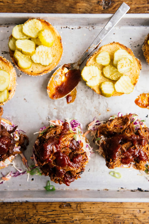 Load image into Gallery viewer, pulled pork sandwiches topped with slaw, pickles and bbq sauce