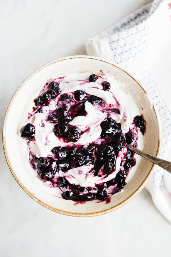 a bowl of yogurt with blueberry compote mixed throughout