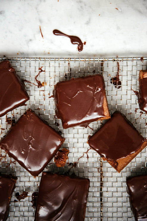 Load image into Gallery viewer, sliced brownies on a cooling rack topped with chocolate fudge sauce