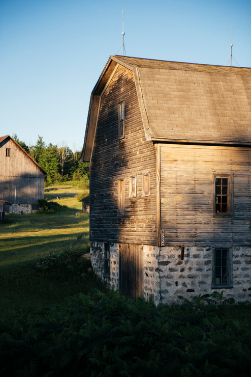 Load image into Gallery viewer, an old wooden and stone barn in a field