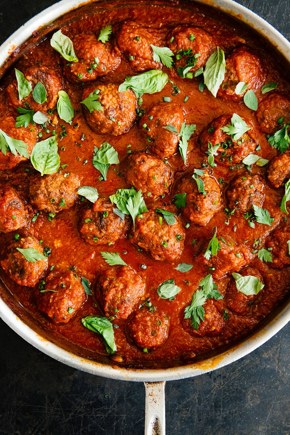 Homemade meatballs and sauce simmering in a shallow pan