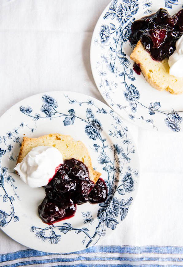 slices of pound cake on plates topped with homemade whipped cream and fruit perfect blueberries