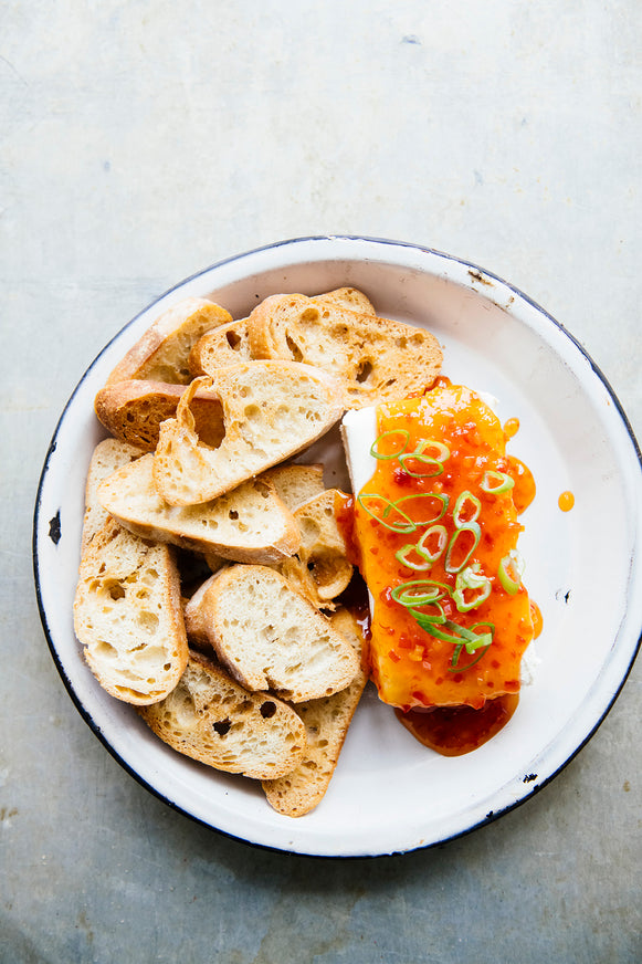 baguette slices next to cream cheese topped with jalapeno pepper jelly