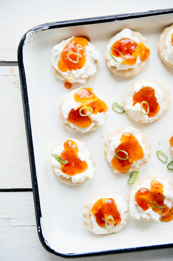a tray of crackers topped with cream cheese and pepper jelly