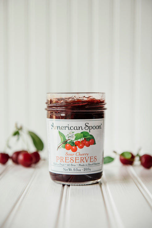 Load image into Gallery viewer, a jar of sour cherry preserves with fresh cherries in the background