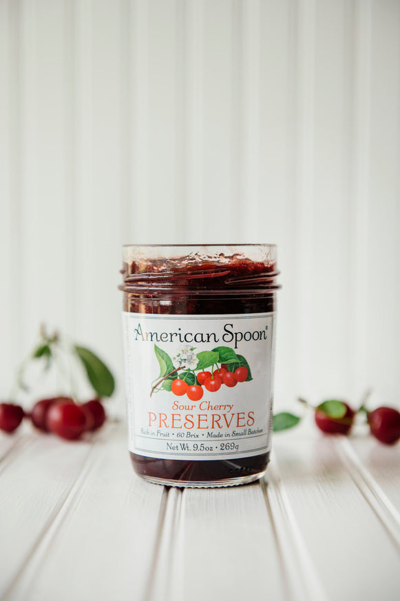 a jar of sour cherry preserves with fresh cherries in the background