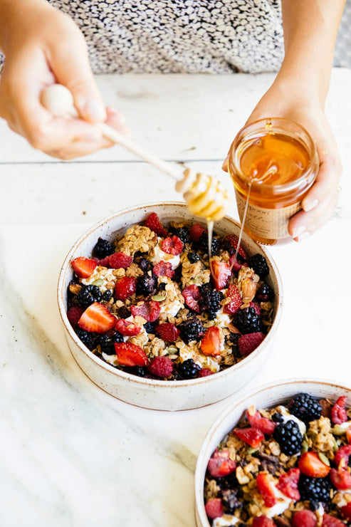 Load image into Gallery viewer, a bowl of maple granola topped with fresh berries and drizzled with honey