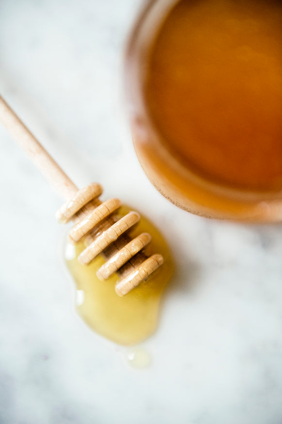 honey dripping off a wooden honey dipper
