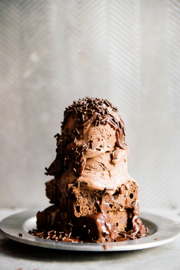 a brownie sundae topped with chocolate fudge sauce and chocolate sprinkles