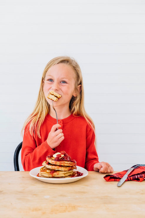 Load image into Gallery viewer, a little girl eating a stack of pancakes topped with fruit perfect sour cherries
