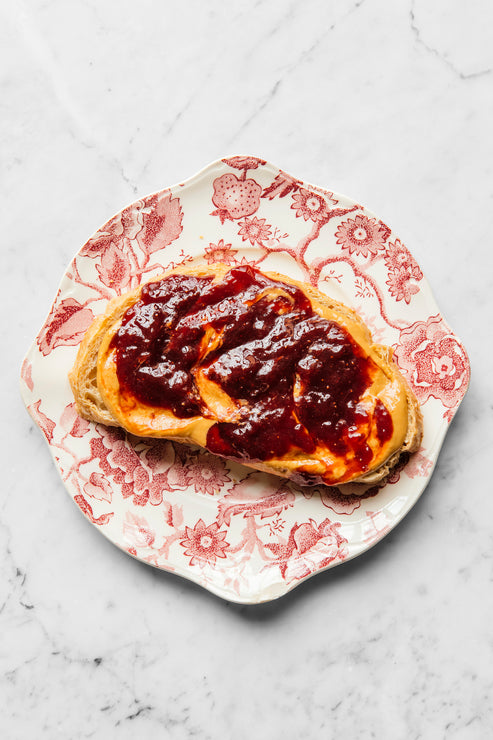 Load image into Gallery viewer, A piece of toast on a plate topped with peanut butter and jam