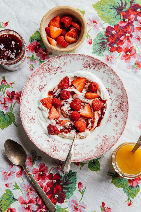 a bowl of yogurt topped with strawberry preserves and fresh strawberries