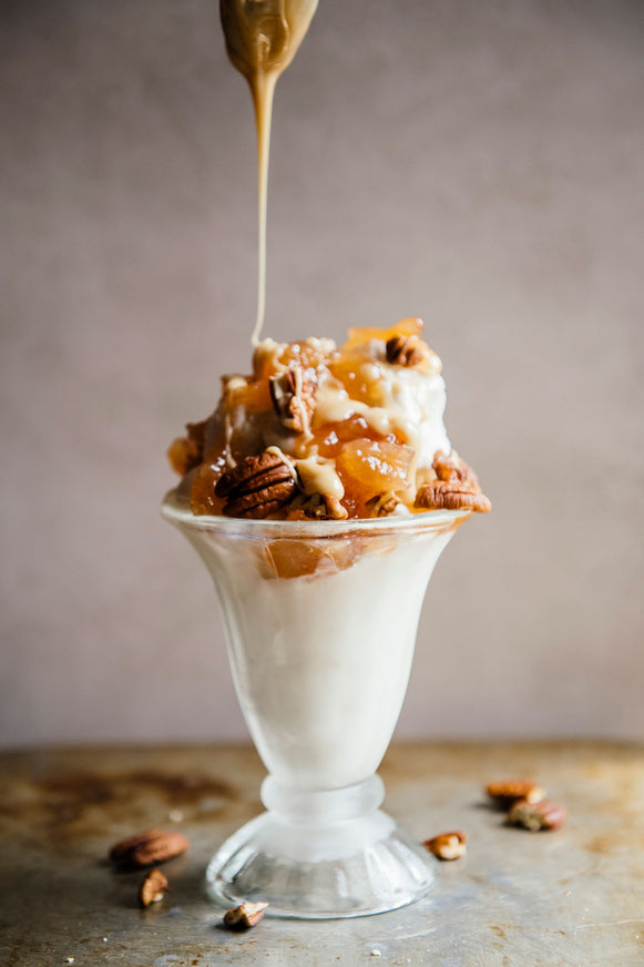 an ice cream sundae topped with salted maple caramel and pecans
