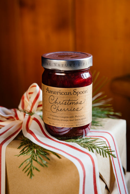 Load image into Gallery viewer, a jar of christmas cherries on a kraft paper package with ribbon and greenery
