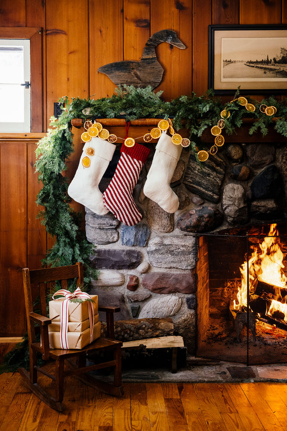 a fire place in a wooden cabin with garland, gifts and stockings