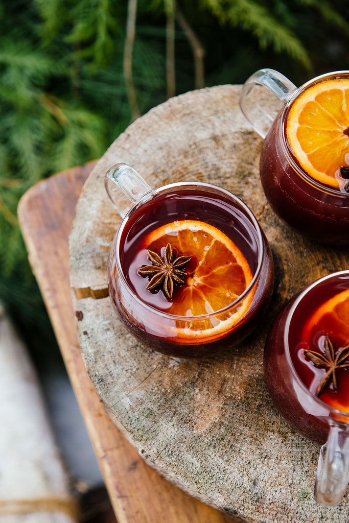 mugs of holiday punch with orange and star anise garnishes