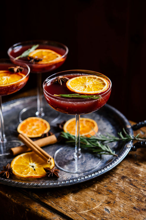 Load image into Gallery viewer, coupe glasses of holiday punch with garnishes on a silver tray.