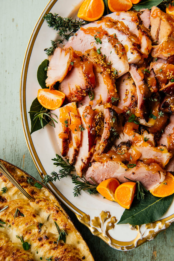 Orange Marmalade glazed ham on a platter with orange garnishes