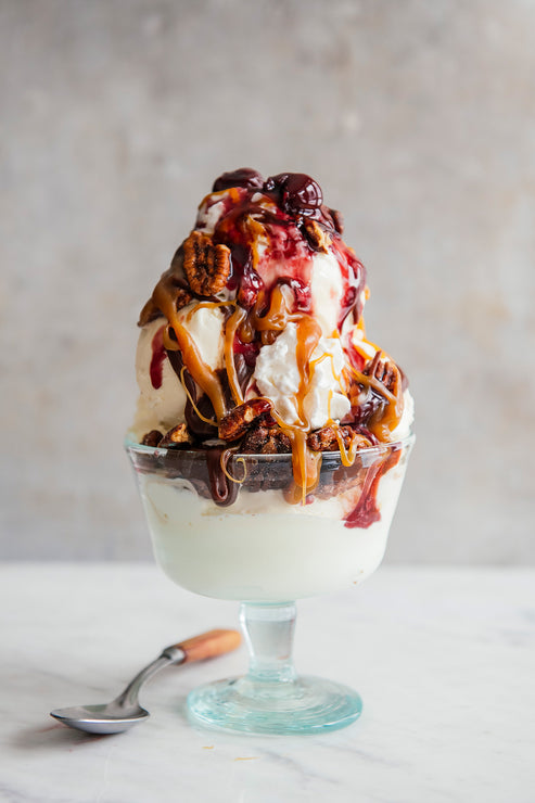 Load image into Gallery viewer, An ice cream sundae topped with cherries, pecans, caramel and fudge sauce
