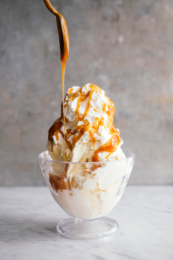 ice cream topped generously with whipped cream and Boozy Butterscotch