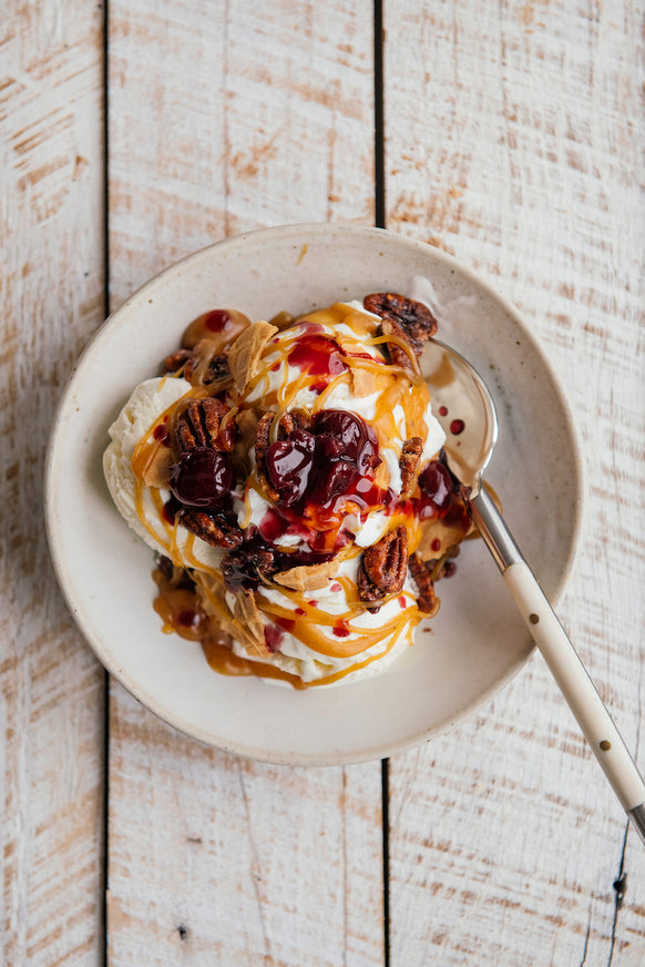 vanilla ice cream sundae topped with brandied cherries, candied pecans and salted maple caramel