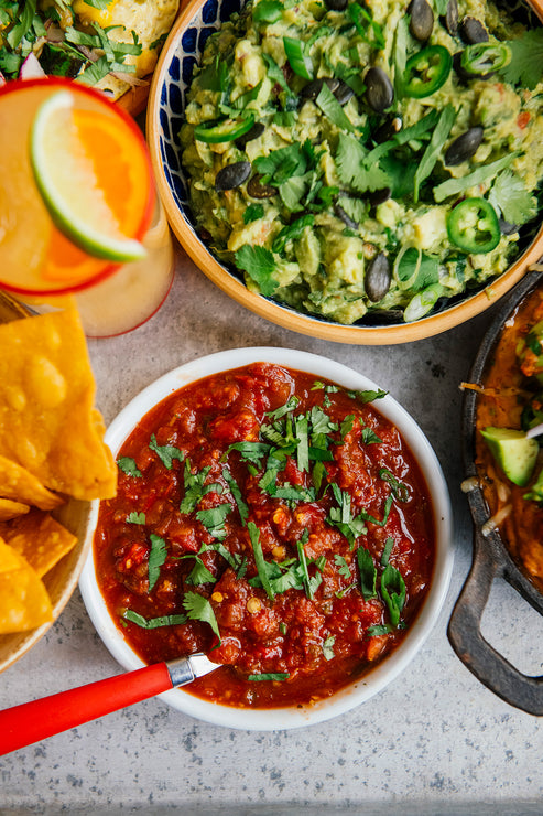 Load image into Gallery viewer, bowls of cherry peach salsa topped with cilantro and homemade guacamole with tomatillo salsa next to a margarita and bowl of chips