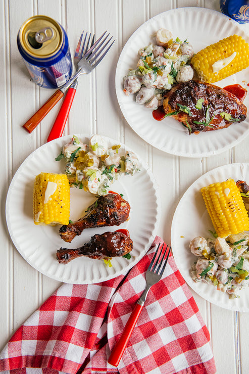 Load image into Gallery viewer, plates of bbq chicken drumsticks and thighs next to corn and potato salad