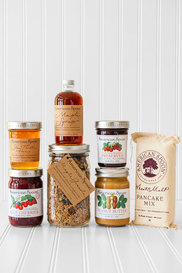 American Spoon products stacked together - Star Thistle Honey, Fruit Perfect Sour Cherries, Maple Granola, Maple Syrup, Early Glow Strawberry Preserves, Peanut Butter and Wheat & Malt Pancake Mix