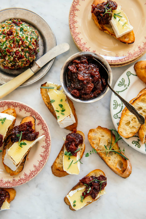 Load image into Gallery viewer, a cheese ball next to sliced baguette topped with brie and holiday jam