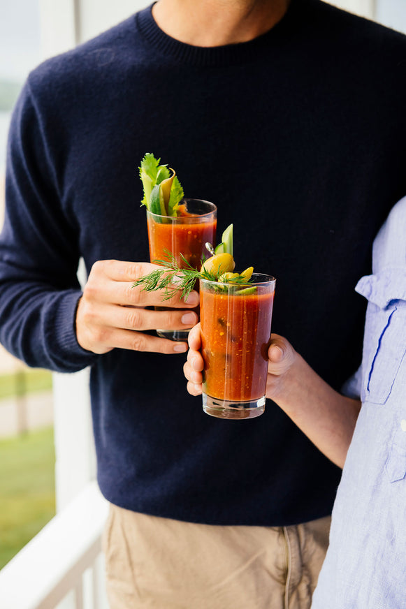 two people with glasses of bloody mary mix on a porch