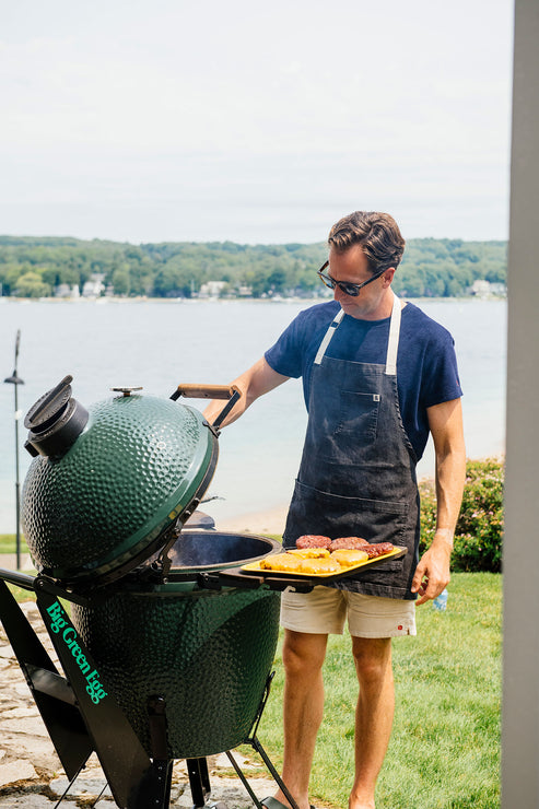 Load image into Gallery viewer, a man standing at a grill with water in the background