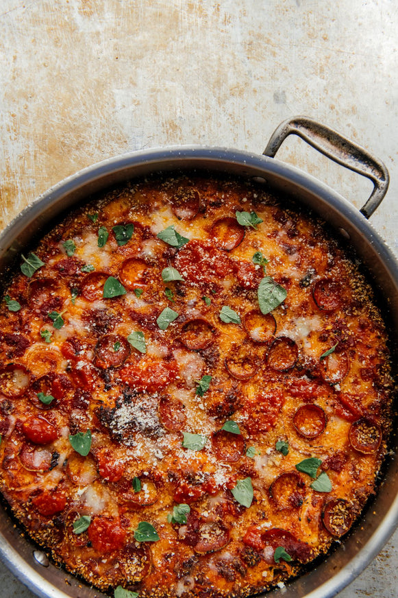 Pizza Pie with pepperoni and cheese in a pan on a textured surface.