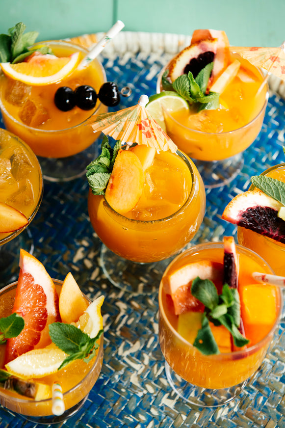 a platter of summer cocktails with fresh fruit garnishes