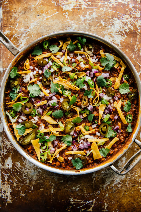 Load image into Gallery viewer, a pot of the People&#39;s Chili topped with tortilla chips, fresh cilantro, and pickled jalapeno slices 
