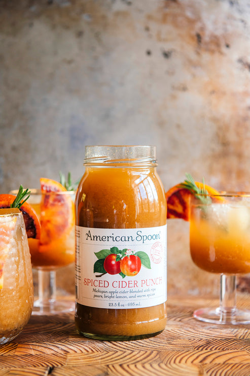 Load image into Gallery viewer, Jar of American Spoon Spiced Cider Punch on a wooden surface with glasses of cider in the background.