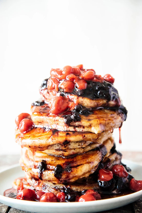 Stack of pancakes topped with Fruit Perfect Sour Cherries, Fruit Perfect Blueberries and Maple Syrup