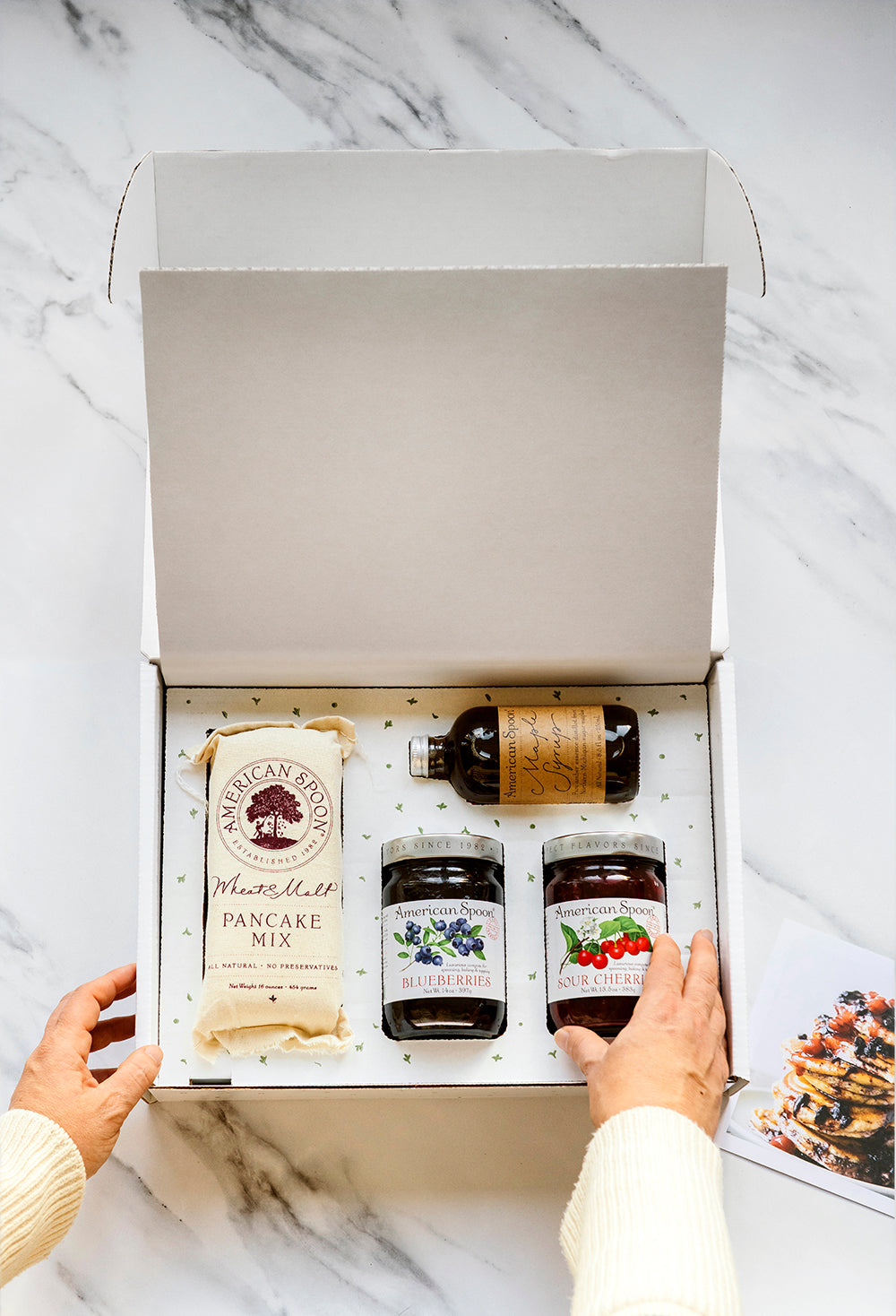 someone opening a classic pancake breakfast box with Wheat & Malt Pancake Mix, Maple Syrup, Fruit Perfect Blueberries and Fruit Perfect Sour Cherries
