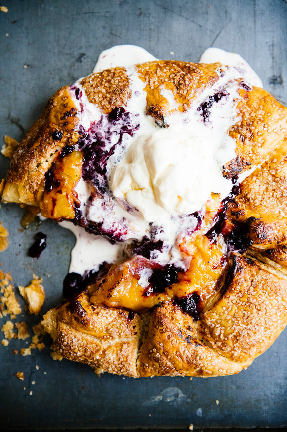 A homemade peach galette topped with Fruit Perfect Blackberries and vanilla ice cream