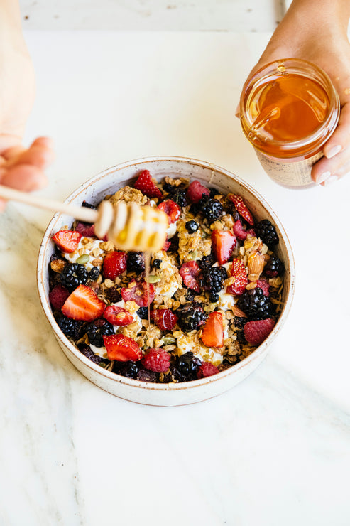Load image into Gallery viewer, A bowl of yogurt with Maple Granola and fresh berries with honey being drizzled over top
