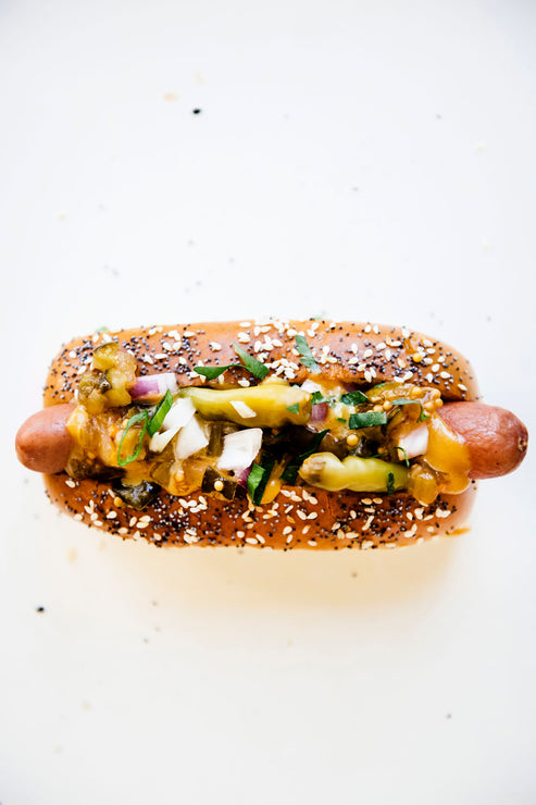 Load image into Gallery viewer, A hot dog topped with peppers, onion, and American Spoon mustard
