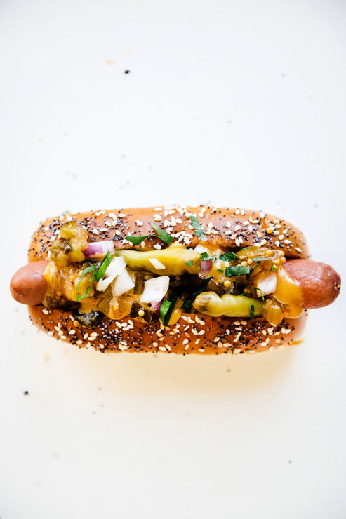 Load image into Gallery viewer, A hot dog topped with peppers, onion, and American Spoon mustard