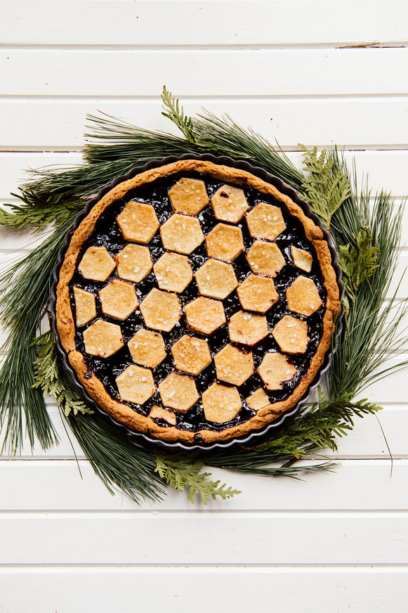 Homemade berry pie surrounded by evergreens