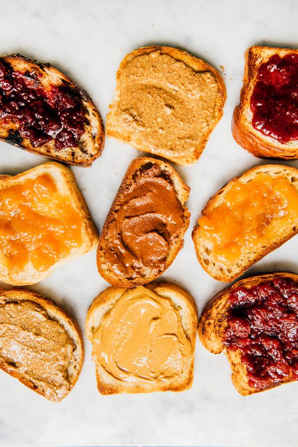 Slices of toast with Chocolate Hazelnut Butter, Almond Butter, Peanut Butter and preserves spread on top