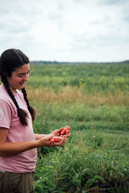 Load image into Gallery viewer, A young women holding freshly picked peppers in a field
