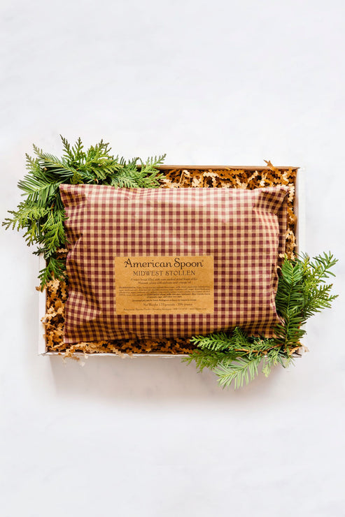 Load image into Gallery viewer, The Midwest Stollen in a gift box, wrapped in red gingham paper and surrounded by sprigs of greenery
