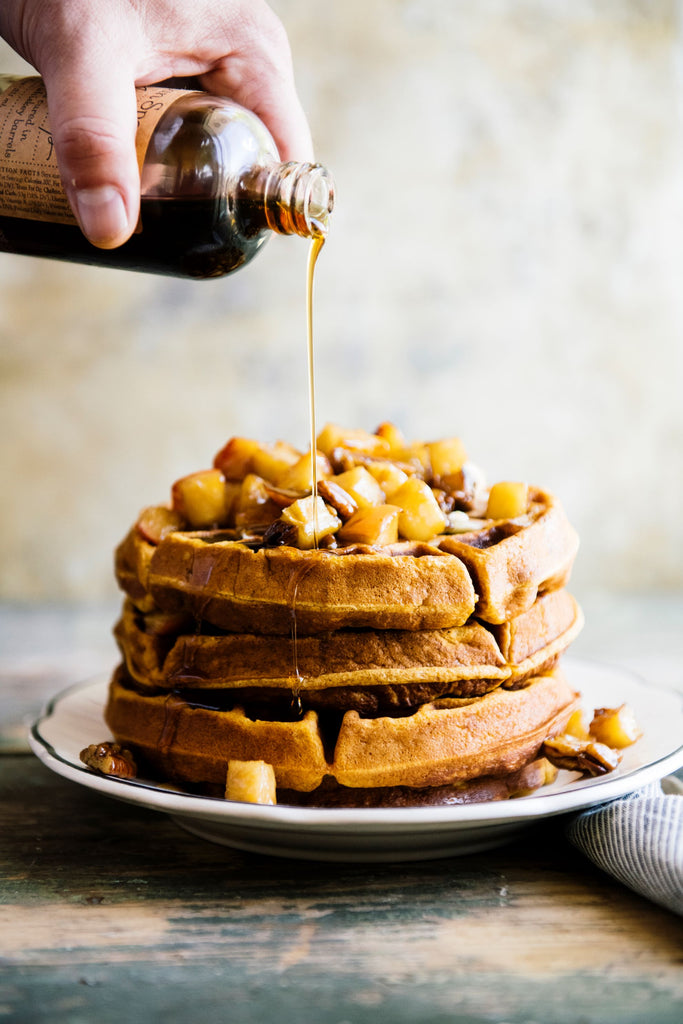 a stack of waffles topped with maple syrup and cooked apples