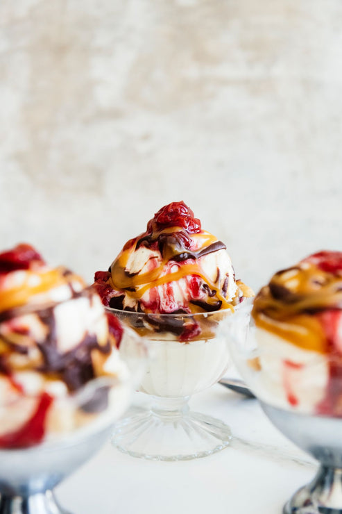Load image into Gallery viewer, Ice cream sundaes topped with cherries, caramel and fudge sauce in glass dishes
