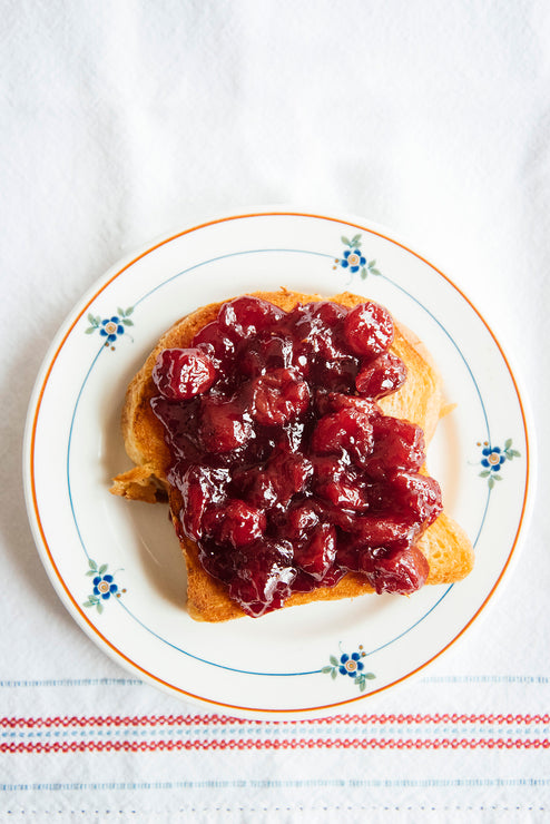 Load image into Gallery viewer, sour cherry preserves spread on toast on a white plate with blue flowers
